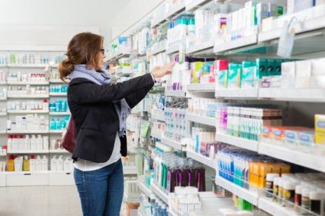 Photo of a lady looking at products on a shelf in a pharmacy