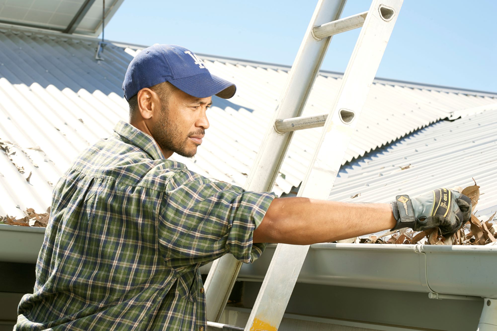 Man on ladder cleaning gutters