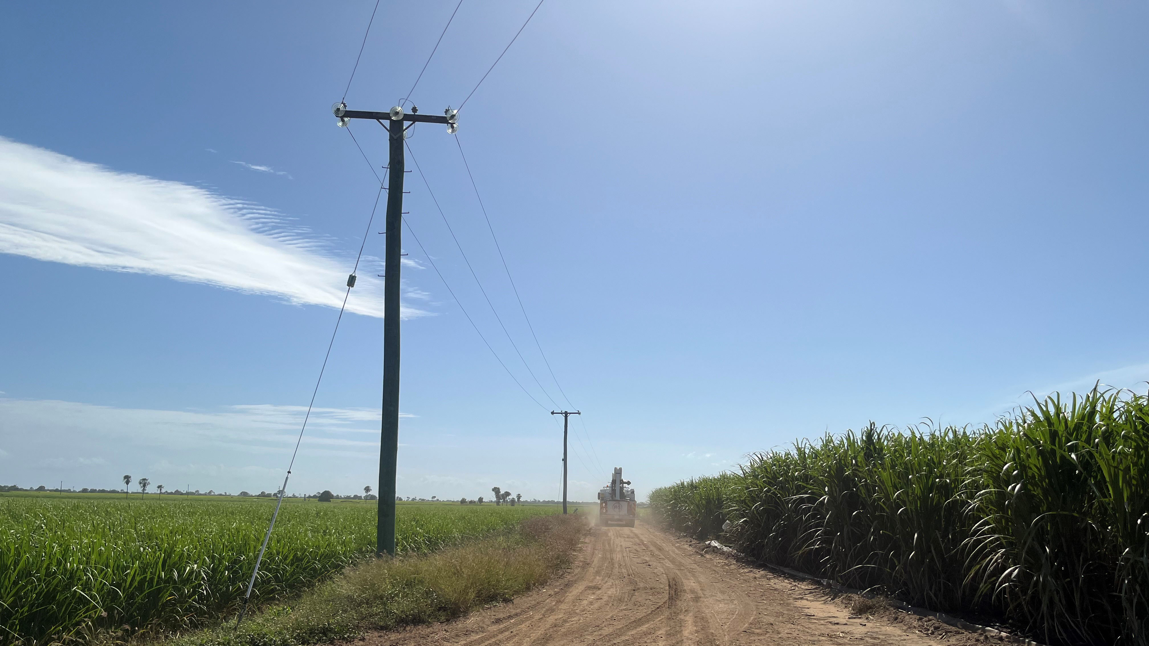 Ergon bucket truck driving past sugar cane fields. 