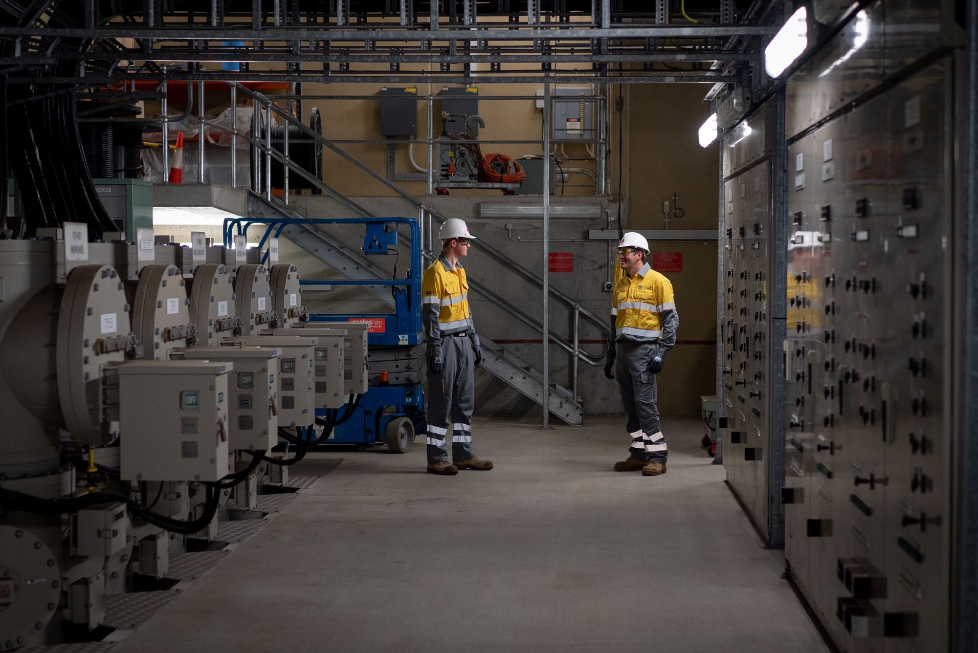 Two field crew standing inside a substation