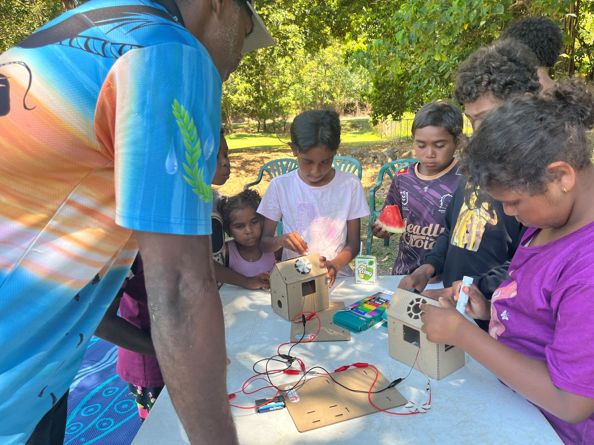 Group of children at a table building a mini replicate of a microgrid