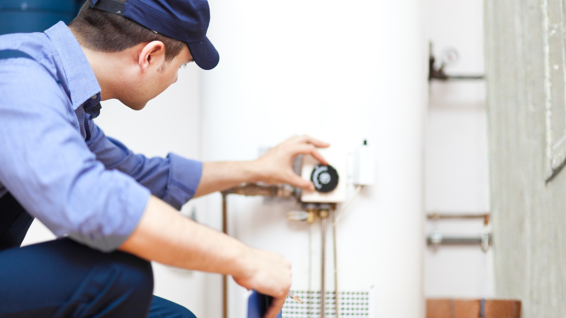 Man with a hat checks dial on a home hot water system