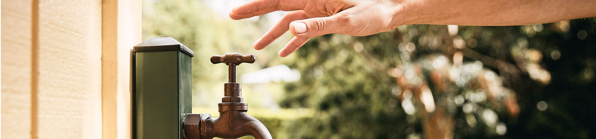 Hand reaching towards outside garden tap