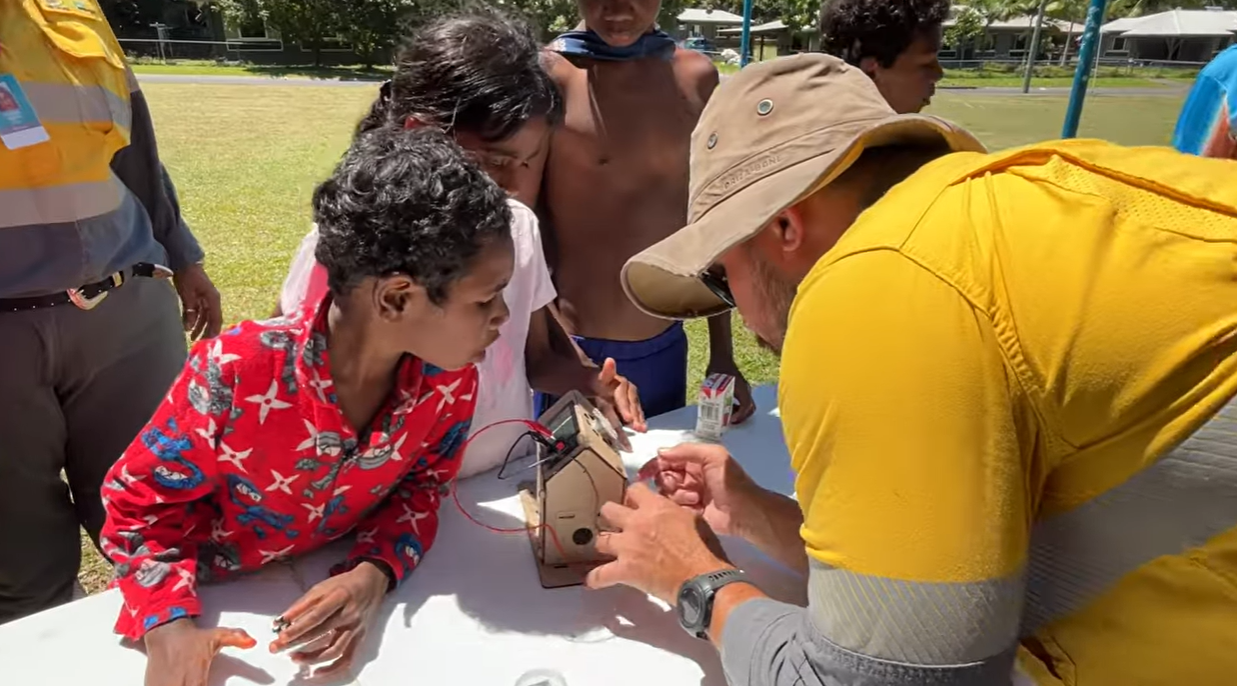 Children and Ergon Energy Network employee looking at craft house on table