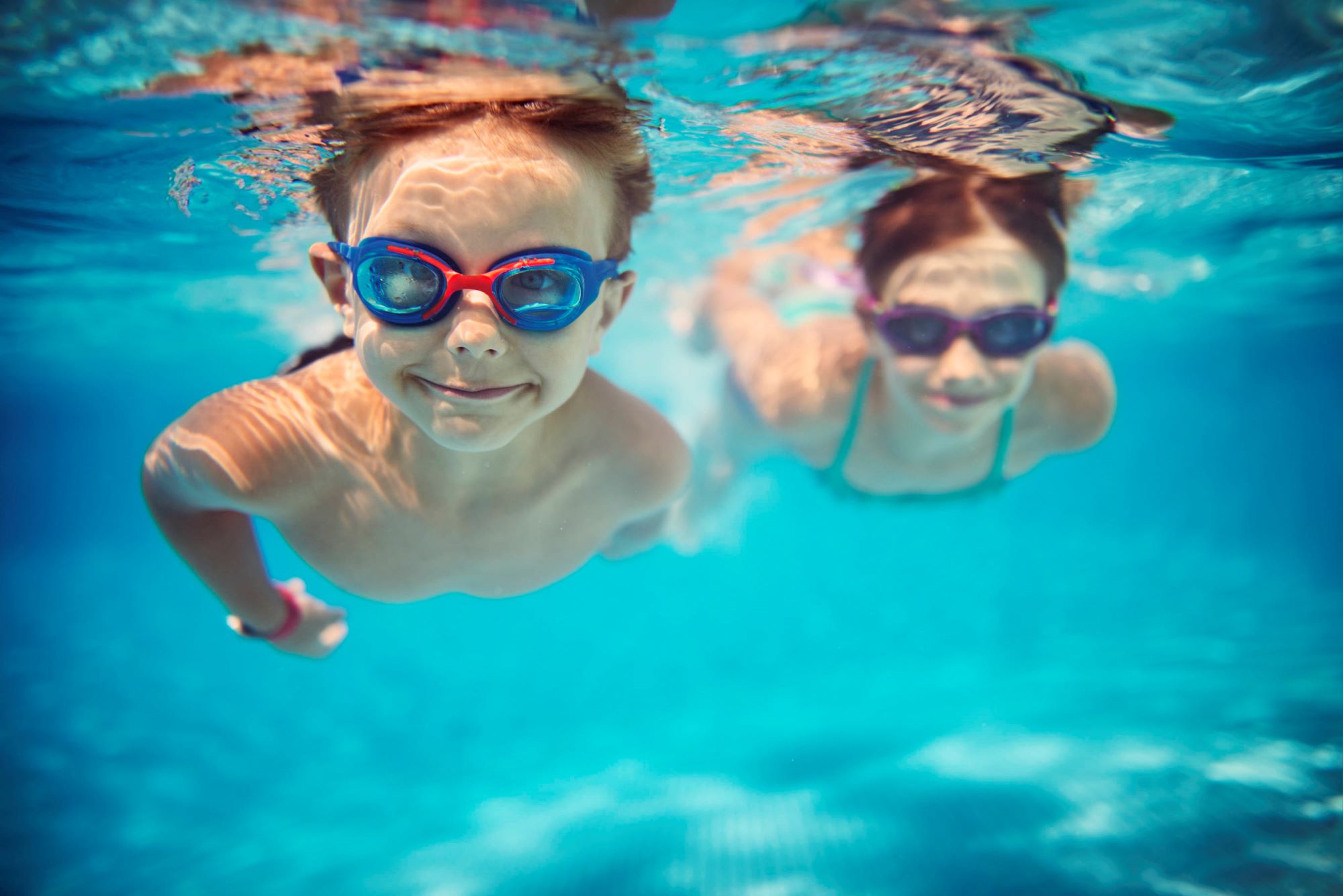 Two children swimming underwater in a pool
