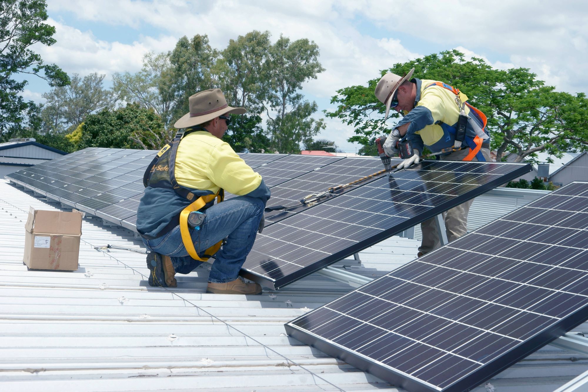 Solar installers drilling in solar panels on a roof