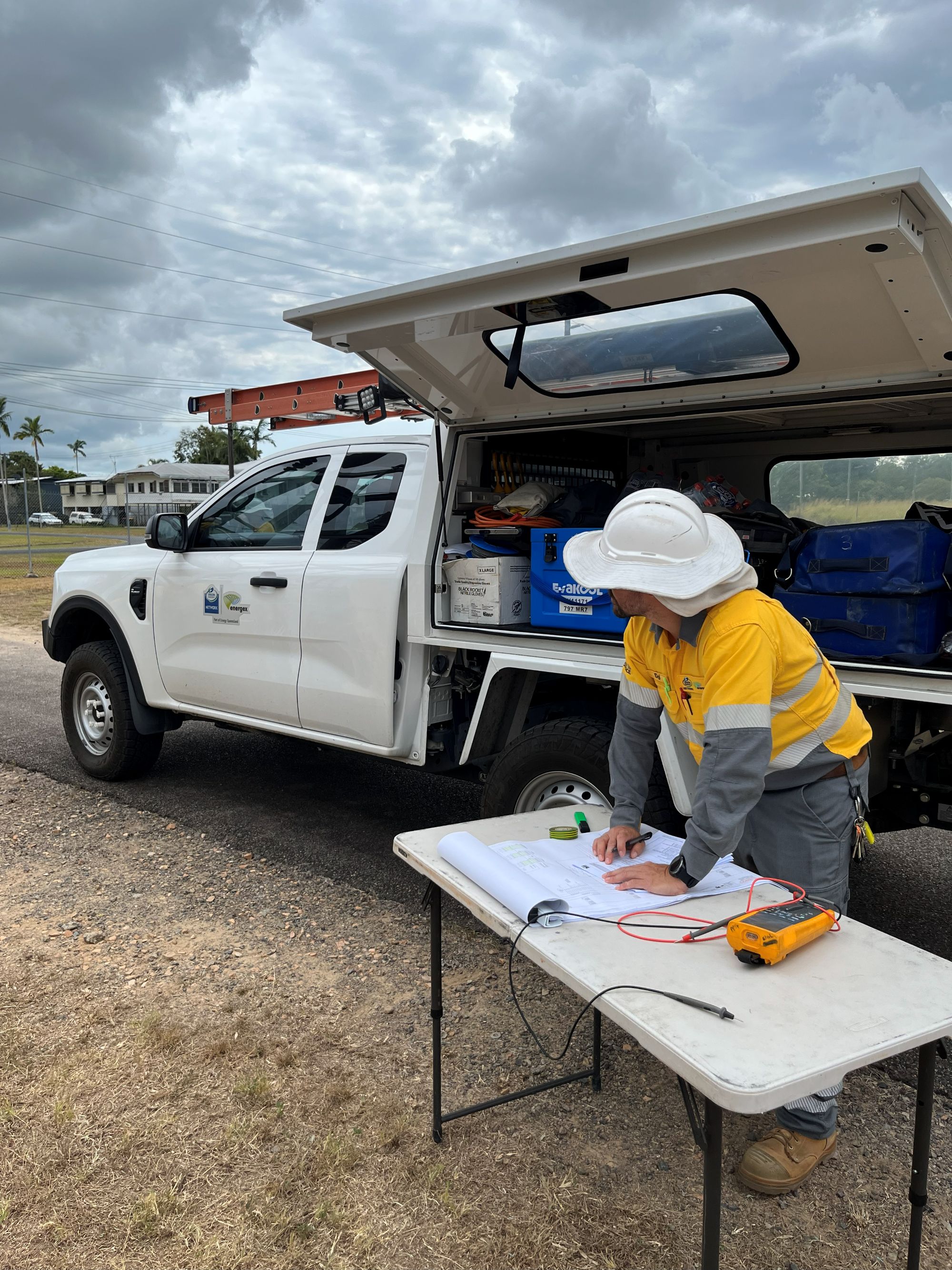 Crew with plans at table near vehicle