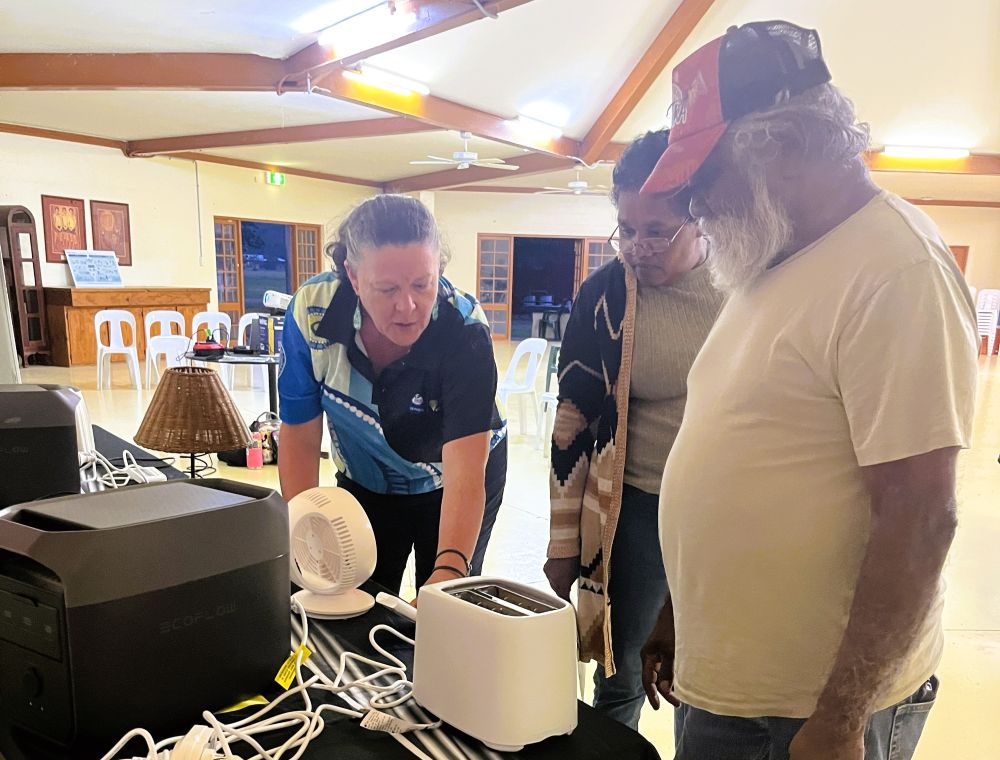 Ergon Energy Network worker with Jumbun locals with appliances on table