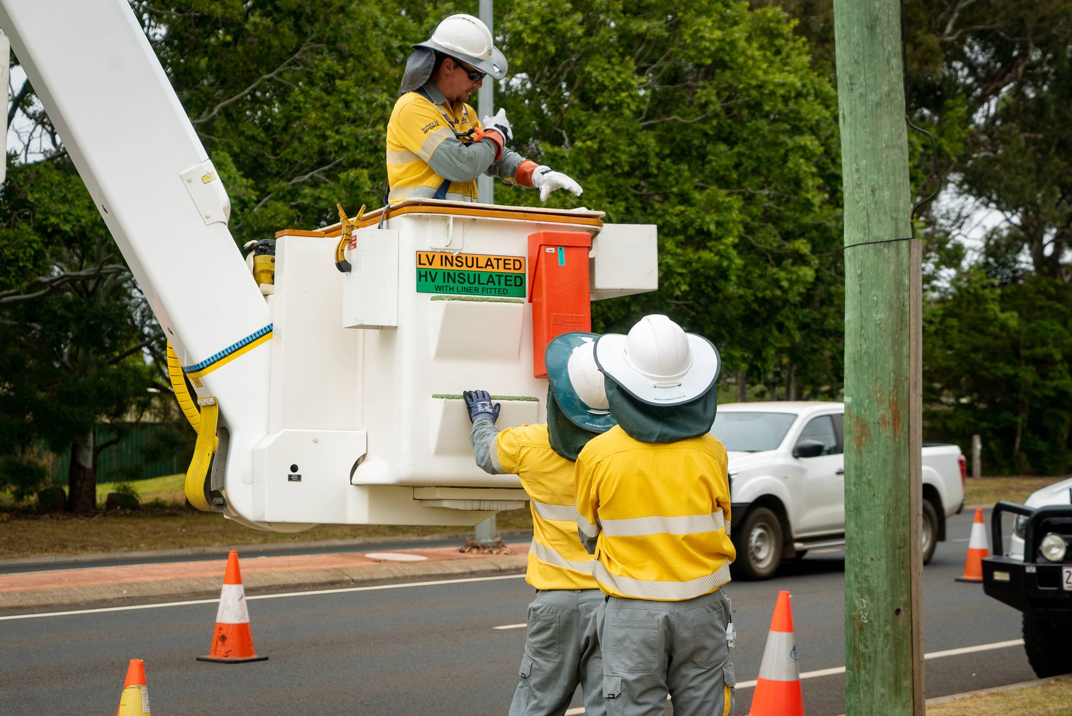 Field crew in cherry picker working next to a road