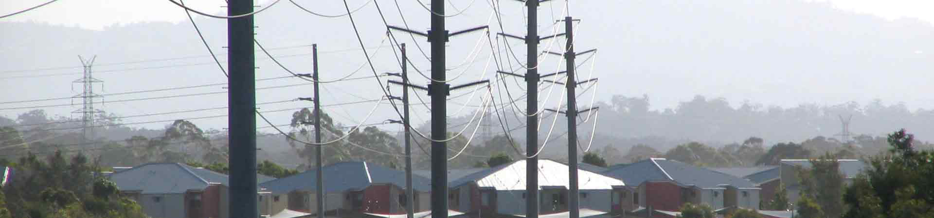 Residential houses in the background with a number of powerlines and power poles