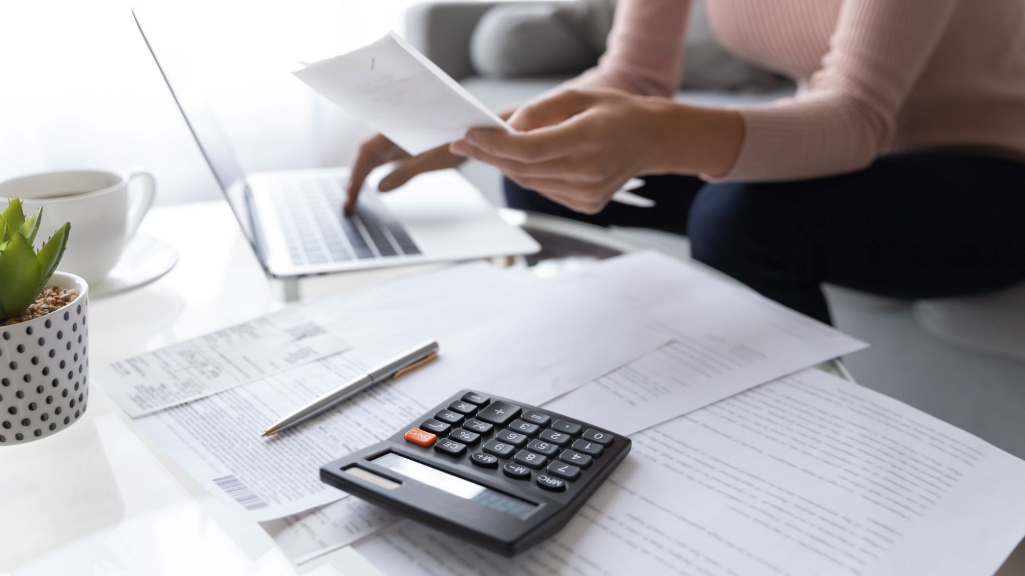 Woman using laptop, pen and calculator