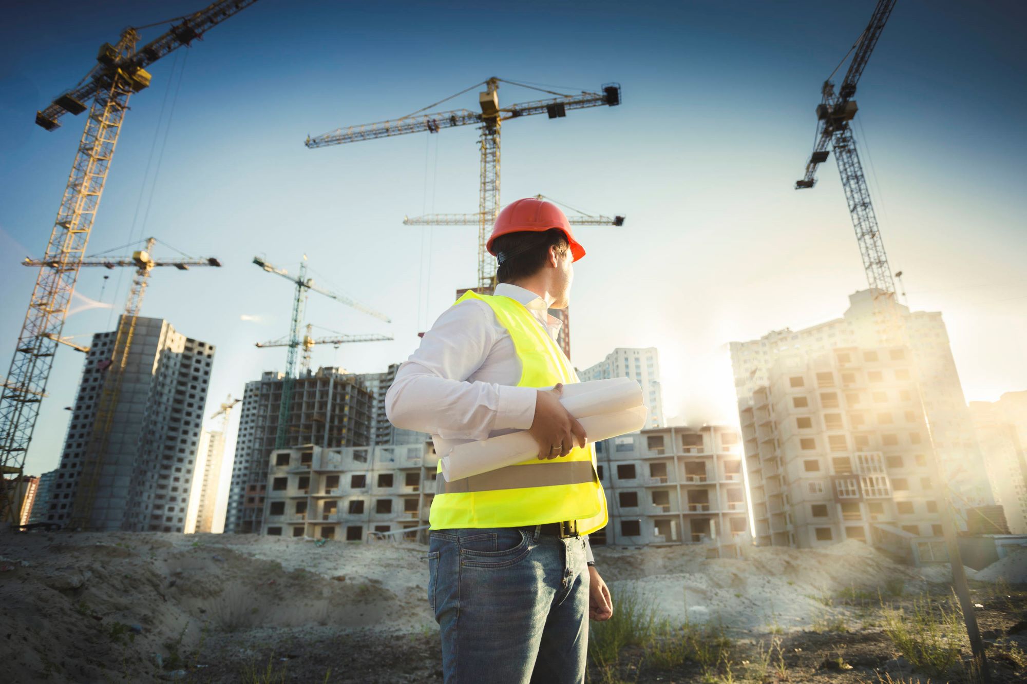 Man in hi-vis vest with buildings under construction in the background