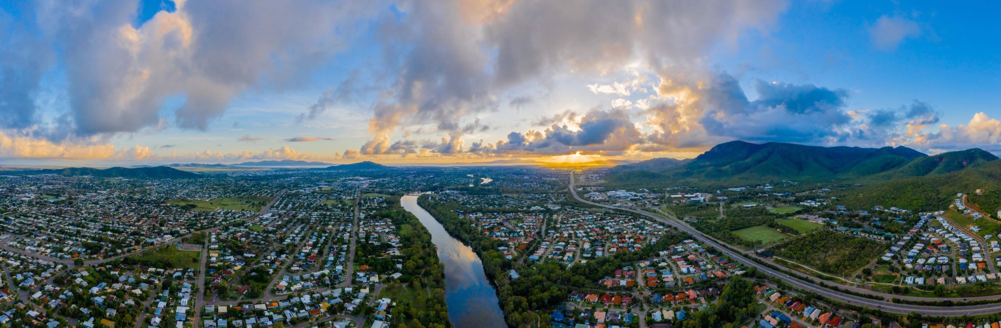 Aerial view of Townsville showing residential houses, river in the middle and mountains on the right