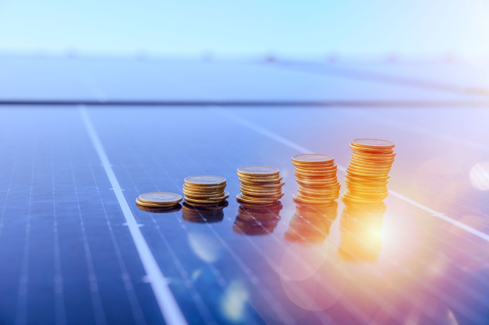 stack of coins on solar panels with sunlight