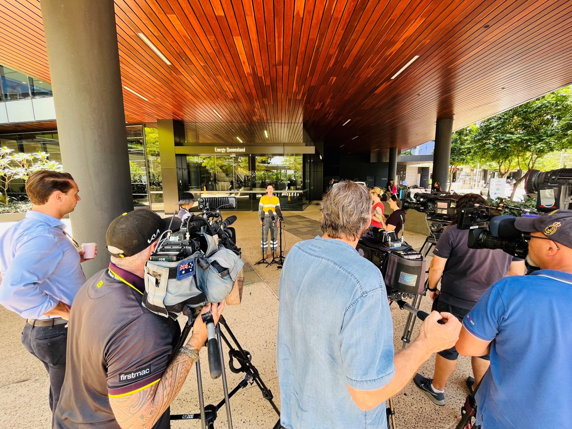 Employee talking to media at the front of a building with media cameras
