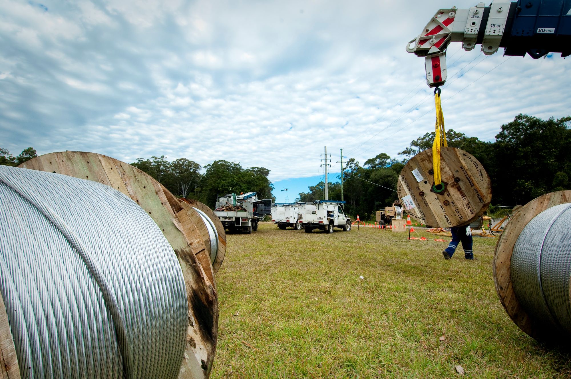 Cable rolls on the ground with power crews in background